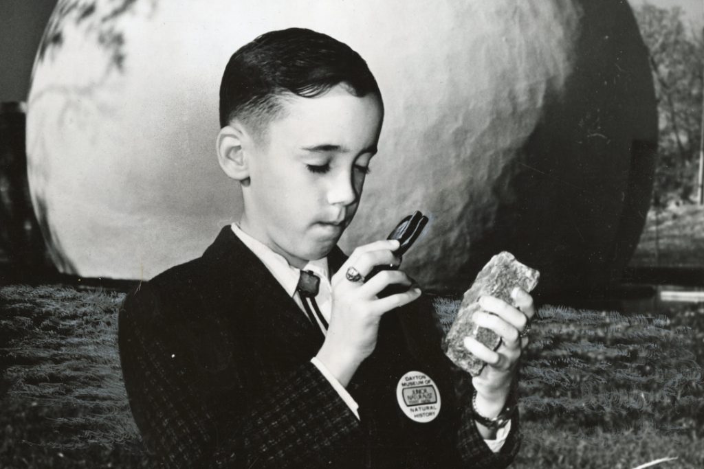 Terry examining the stone in front of a model planet.